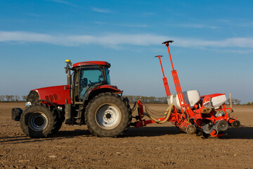 Tractor with sowing machine working on a field. Seeding - sowing crops at agricultural fields in spring.