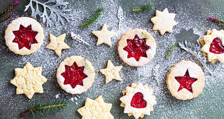 Traditional Linzer Christmas cookies with raspberry jam on green stone background. Top view. Flat lay. Festive decoration.