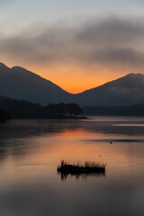 湖に映り込むオレンジ色の朝焼けと雲