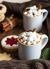 Wooden tray with ceramic cups of hot chocolate or cocoa with marshmallow, cinnamon and anise, shortcrust cookies and pieces of bitter chocolate. Winter time, holiday concept. Selective focus.