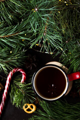 New year's tea party with spices. Red mug with tea surrounded by garlands, fir branches and spices	
