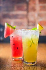 Watermelon and melon smoothies garnished with watermelon slices and mint leaves served in a glass on rustic wooden table