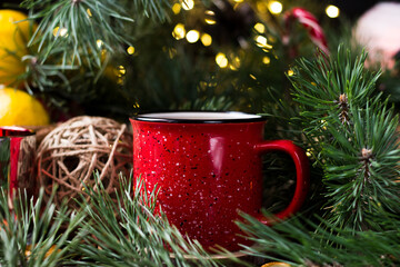 New year's tea party with spices. Red mug with tea surrounded by garlands, fir branches and spices	
