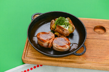 Grilled fillet mignon at the restaurant. Medallion steak dish with baked stuffed potato served in a frying pan.