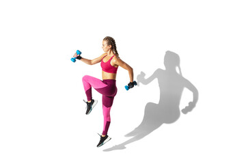 Fototapeta na wymiar Weights. Beautiful young female athlete practicing on white studio background, portrait with shadows. Sportive fit model in motion and action. Body building, healthy lifestyle, style concept.