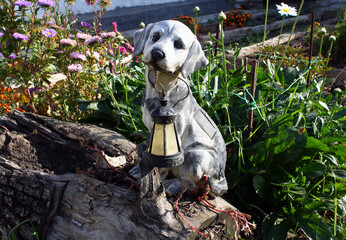 Garden flashlight in the shape of a dog among flowers.