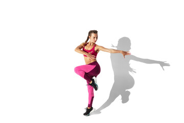 Fototapeta na wymiar Strong. Beautiful young female athlete practicing on white studio background, portrait with shadows. Sportive fit model in motion and action. Body building, healthy lifestyle, style concept.