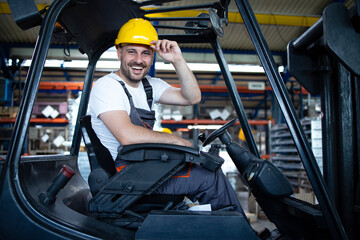 Portrait of smiling professional forklift driver in factory's warehouse. - obrazy, fototapety, plakaty
