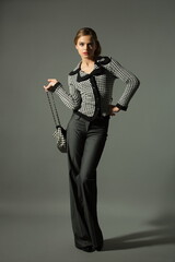 Beautiful girl teenager blonde in a stylish business suit on a gray background