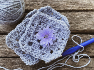 crocheted fragments and flowers on wooden background