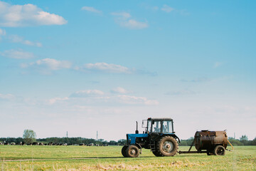 Obraz premium Old Tractor With Tank Rides On Countryside Road. Beginning Of Agricultural Spring Season