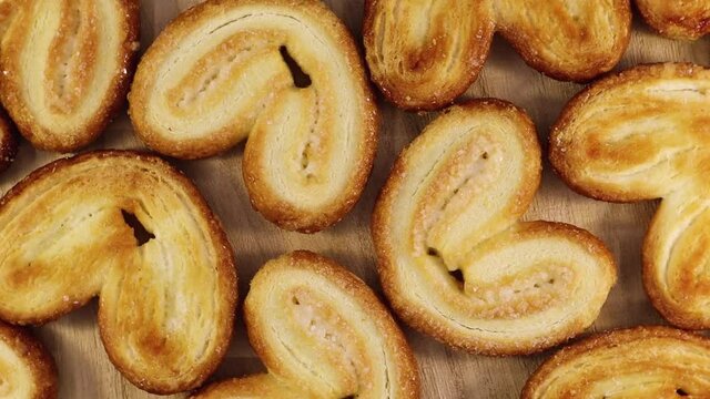Rotating close up of fresh palm puff pastry in the shape of a heart. French biscuits with elephant ears. View from above. Close-up