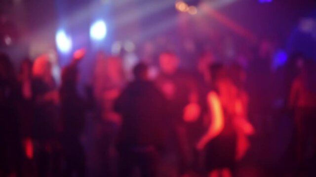 blurred silhouettes of a crowd of dancing people on the dance floor at a live music concert