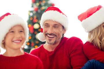 Portrait of positive daddy dad look at his son wear santa claus cap in house with x-mas christmas ornament