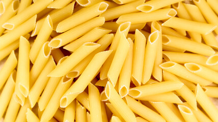 Penne Rigate Raw Pasta is a short pasta with oblique cuts and a ribbed surface. Traditional Italian pasta. Pasta background. Italian food ingredient top view.