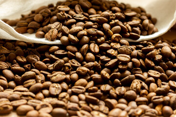 Roasted arabica coffee beans scattered in a heap on the table.