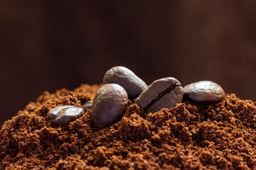 Roasted grains of arabica coffee on the surface of ground coffee.