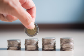 Future plan saving money for 2021 year concept. hand holding coin on blur image of coin and blue background.