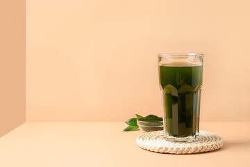 Chlorella Detox drink in glass on modern beige background as cube. Close up.