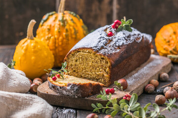 Delicious pumpkin cake on cutting board. Loaf of  bread with pumpkins.