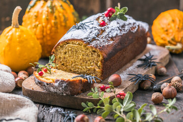Delicious pumpkin cake on cutting board. Loaf of  bread with pumpkins. Halloween food