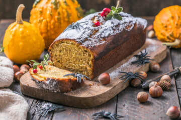 Delicious pumpkin cake on cutting board. Loaf of  bread with pumpkins. Halloween food