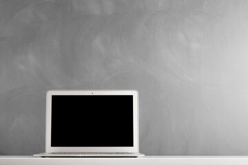 modern laptop computer on the tabl on the blackboard background