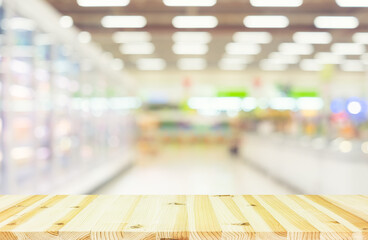 Supermarket or retail store blur abstract background include wood table. In frozen food section. That is a shop offer variety of frozen food in freezer such as dairy, ice cream, meat, vegetable etc.