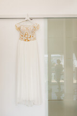 White wedding dress with a lace corset on a hanger with lavender on a glossy texture background with the reflection of the bride's figure.