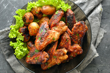 Chicken wings baked in soy-honey sauce. Fried chicken wings in a plate. Top view. Grey background. Free space for text.