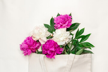 Cotton eco bag with peony flowers on white background Zero waste concept. Flat lay. Top view