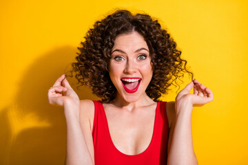 Portrait photo of pretty cute nice girl with afro curly hairdo touching her curls smiling shouting happily wearing make-up with red lipstick isolated on bright yellow color background