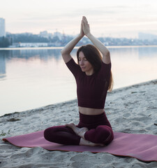 Young woman doing Hatha yoga on the beach in the morning. Outdoor meditation