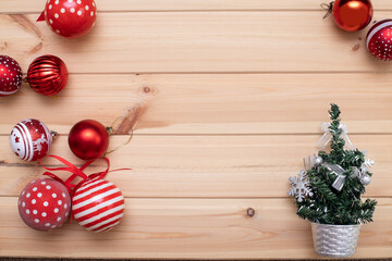 Christmas card. A green Christmas tree in a Silver pot on a light wooden background in the lower right corner , and red Christmas balls are scattered in the left corner. Flat bed, top view, copy space