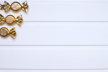 Christmas card. In the upper left corner, three Golden Christmas toys in the form of sweets are placed on a white wooden background. Flat bed, top view, copy space. Christmas frame, new year's banner 