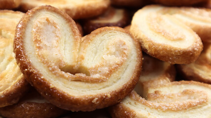 Fresh puff pastry palm cookies in the shape of a heart. Classic French pastries. Pig ear, elephant ear cookies, French hearts. View from above