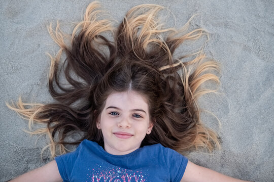 portrait of a girl lying in the sand with dyed hair