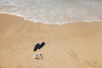 Swim goggles and water shoes on sea shore