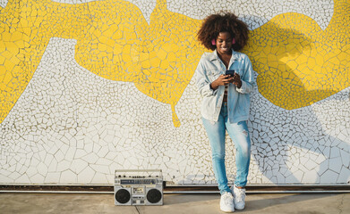 Young african woman listening music outdoor with smartphone app - Technology and stylish lifestyle...