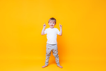 Cute boy on yellow background points with his hand to the side, photo for advertising product