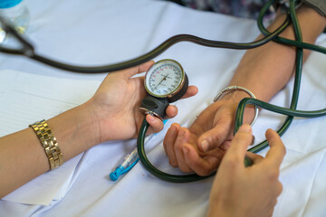 Volunteer nurse measuring blood pressure of poor Asian people outdoors closeup