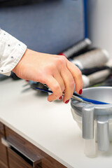 Hand of hairstylist prepares dye in bowl for coloring hair in hairdress salon