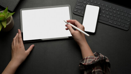 Female working on mock up digital tablet on black table with mock up smartphone and keyboard