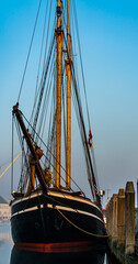 Classic old wooden tall ship moored at port in the morning light.