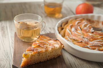 Heap of homemade apple pie close-up and copy space. A quick autumn dessert idea with tea. Autumn pie with apples, Rustic wooden background.
