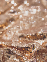 Close up picture of rose gold sequin with blur effect. Bokeh lights defocused. Gold shade with sparkling effect on the background. Picture for wallpaper. Fabric closely with shimmering light.