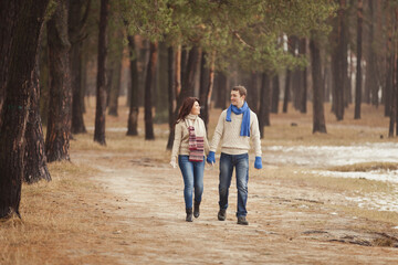 couple in winter play in snow and hugging near the pine. Two lovers with a toy bear. Valentine's Day  for couple in rustic style. Winter lovestory. Casual outfit with Blue accessories