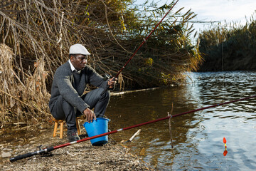Portrait of friendly African man fishing with rods on river
