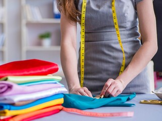 Woman tailor working on a clothing sewing stitching measuring fa