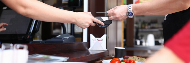 Man pays with plastic card in cafe for lunch at checkout. Secure payment by terminal concept